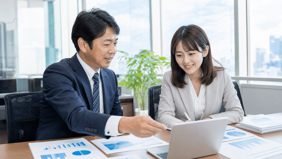 日本人の40代男性経営者と20代の若手女性スタッフが、明るいオフィスでノートパソコンとグラフ資料を一緒に見ながら前向きに打ち合わせをしている場面。デスクには数字の資料。写真風、明るく華やかな雰囲気、ドキュメンタリーテイスト
